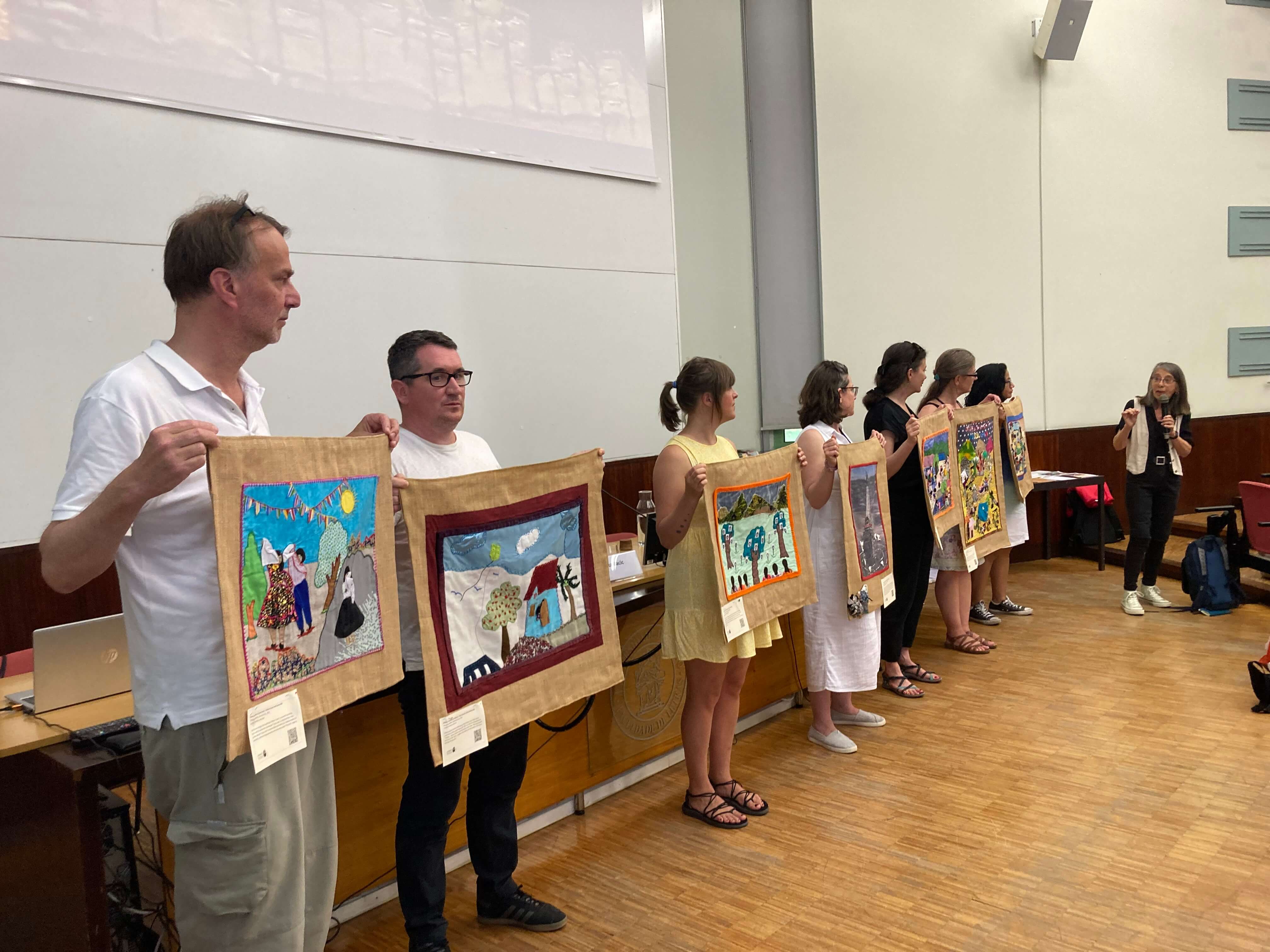 Colleagues holding the 7 arpilleras presented July 4 at Conflict Textiles plenary (Photo: Maija Spurina)